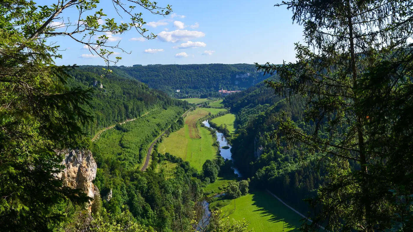 Blick von einem Aussichtspunkt über das Obere Donautal mit Donauschleife, Wiesen und bewaldeten Felshängen
