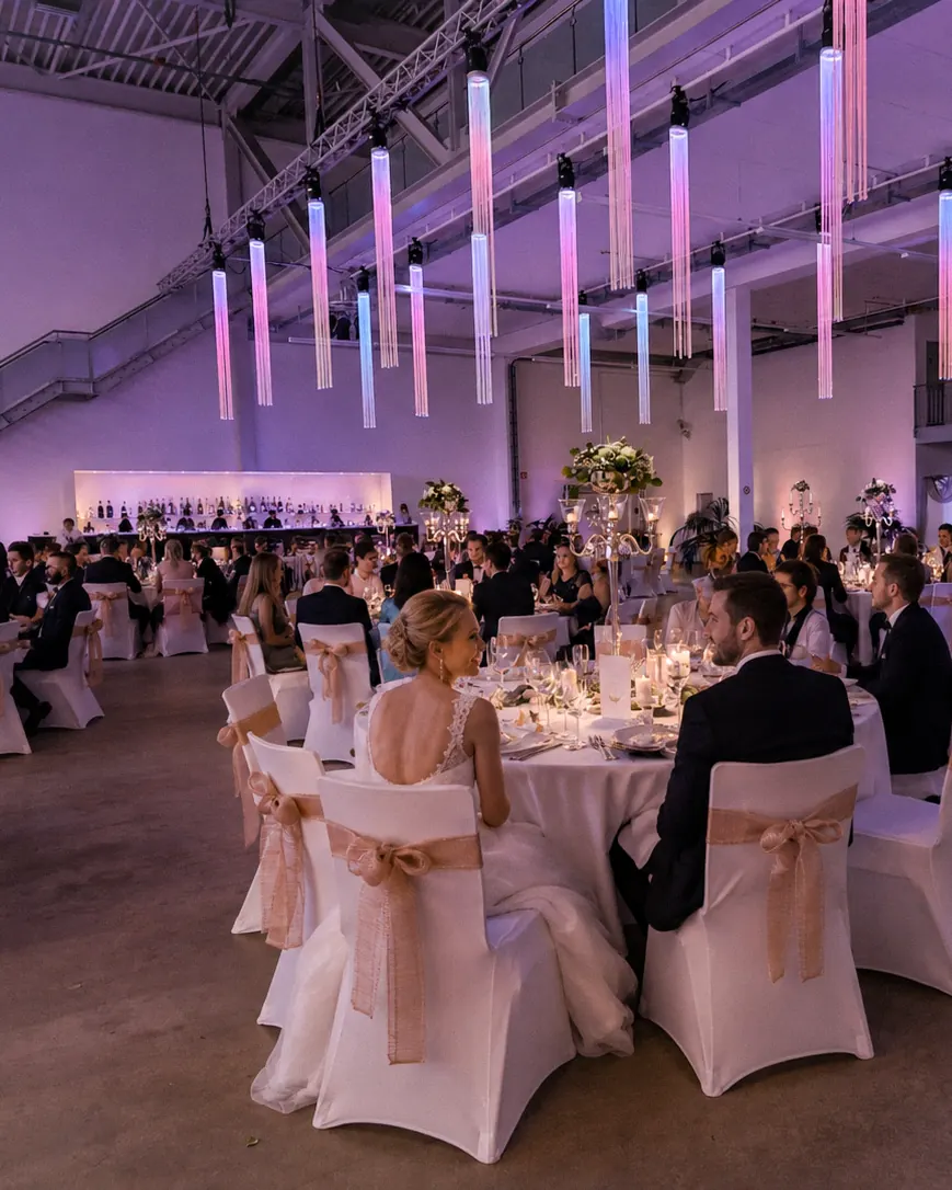 Festlich gedeckte Tafel mit weißen Stuhlhussen im Hangar