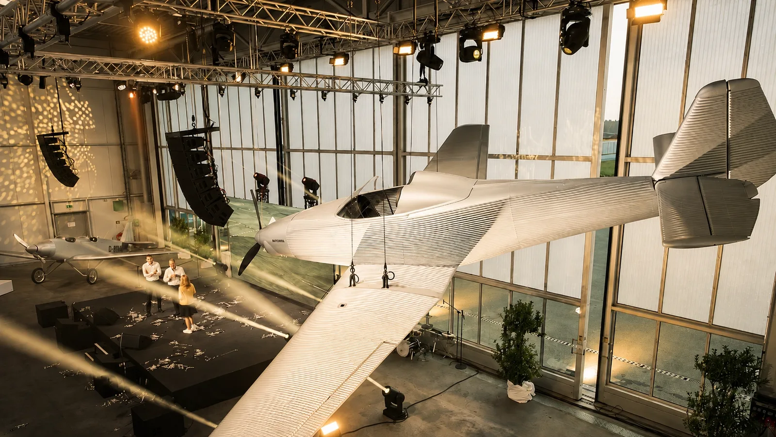 Flugzeug hängt beleuchtet von der Hangardecke über einer nächtlichen Signature-Veranstaltung