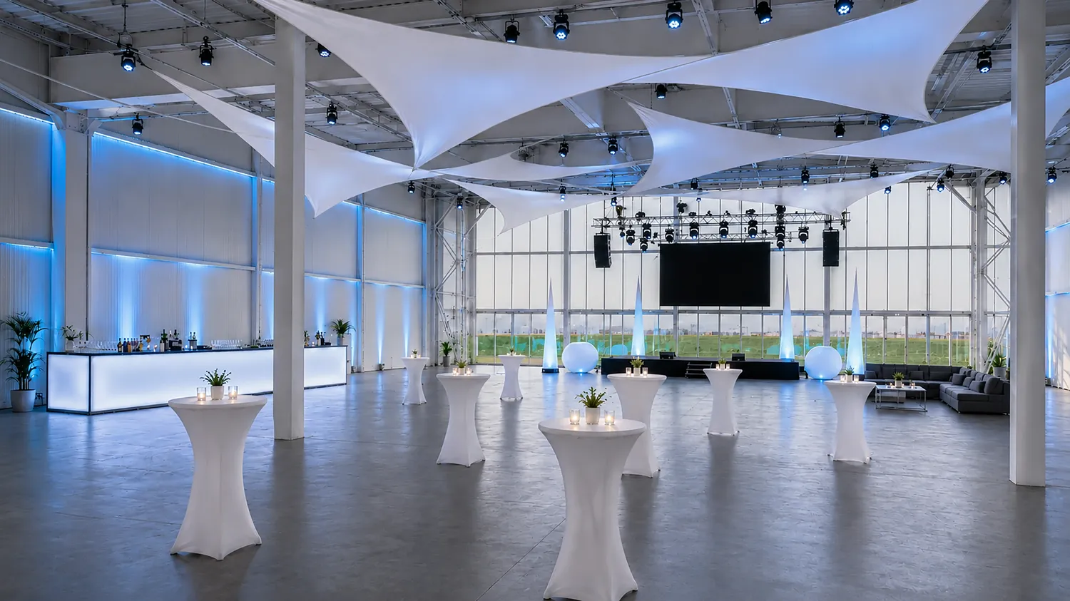 Heller, festlich eingedeckter Hangar mit Lichtsegeln und großen Fensterfronten