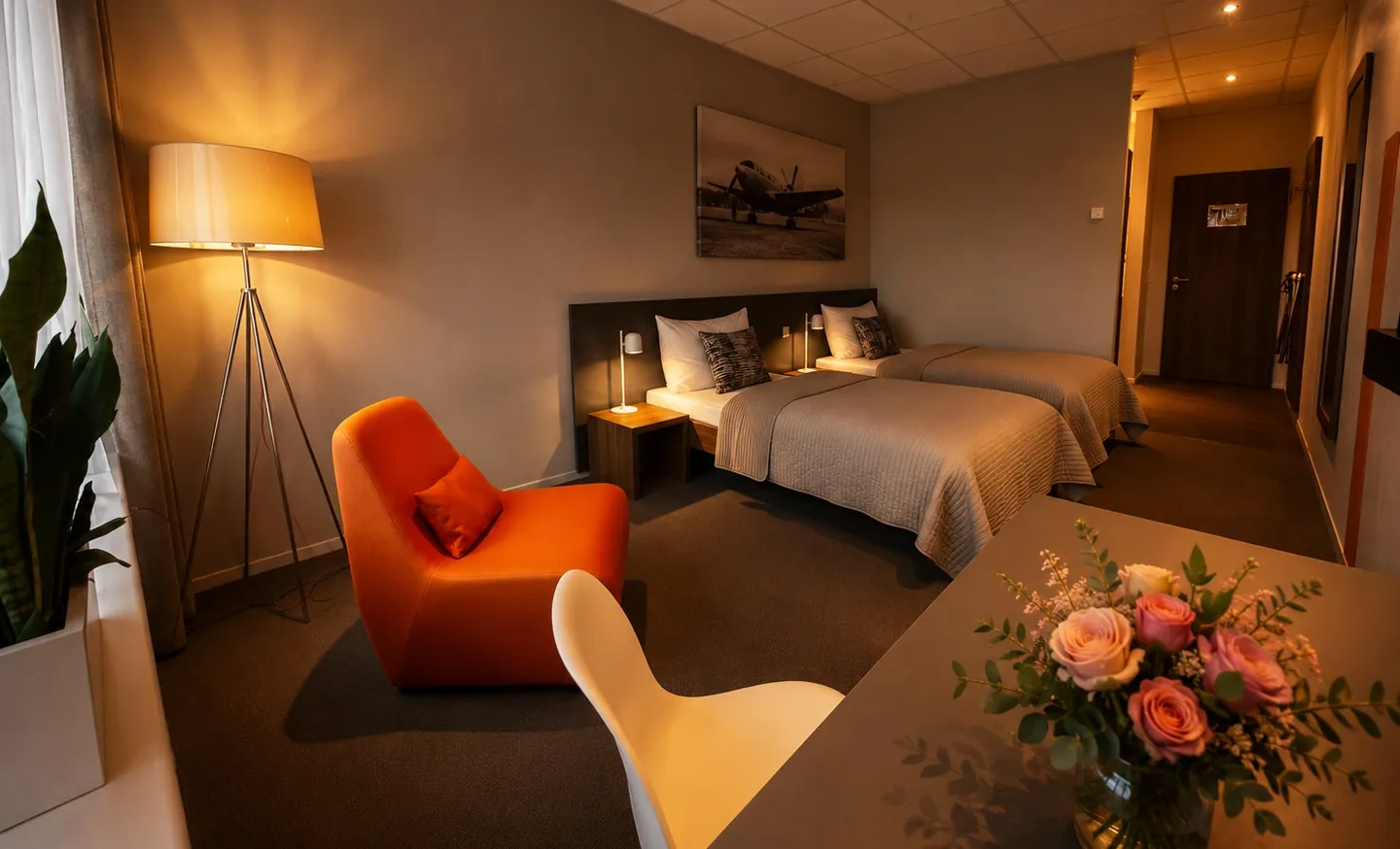 Warm beleuchtetes Hotelzimmer mit Flugzeug-Wandbild und Sitzecke